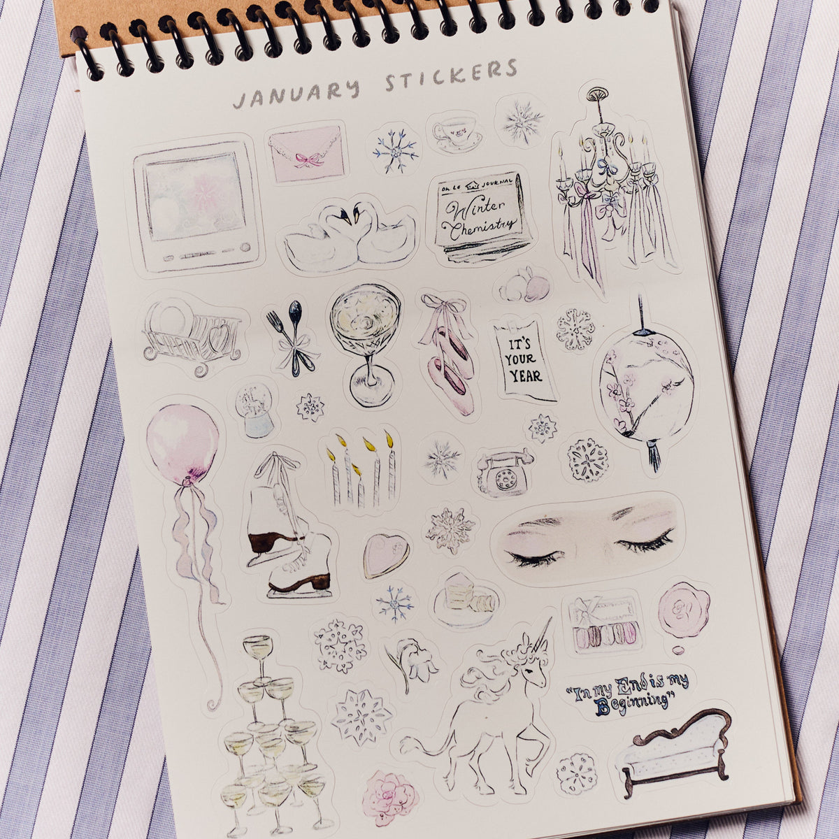 Sheet of January-themed stickers on a spiral-bound book with a striped background.