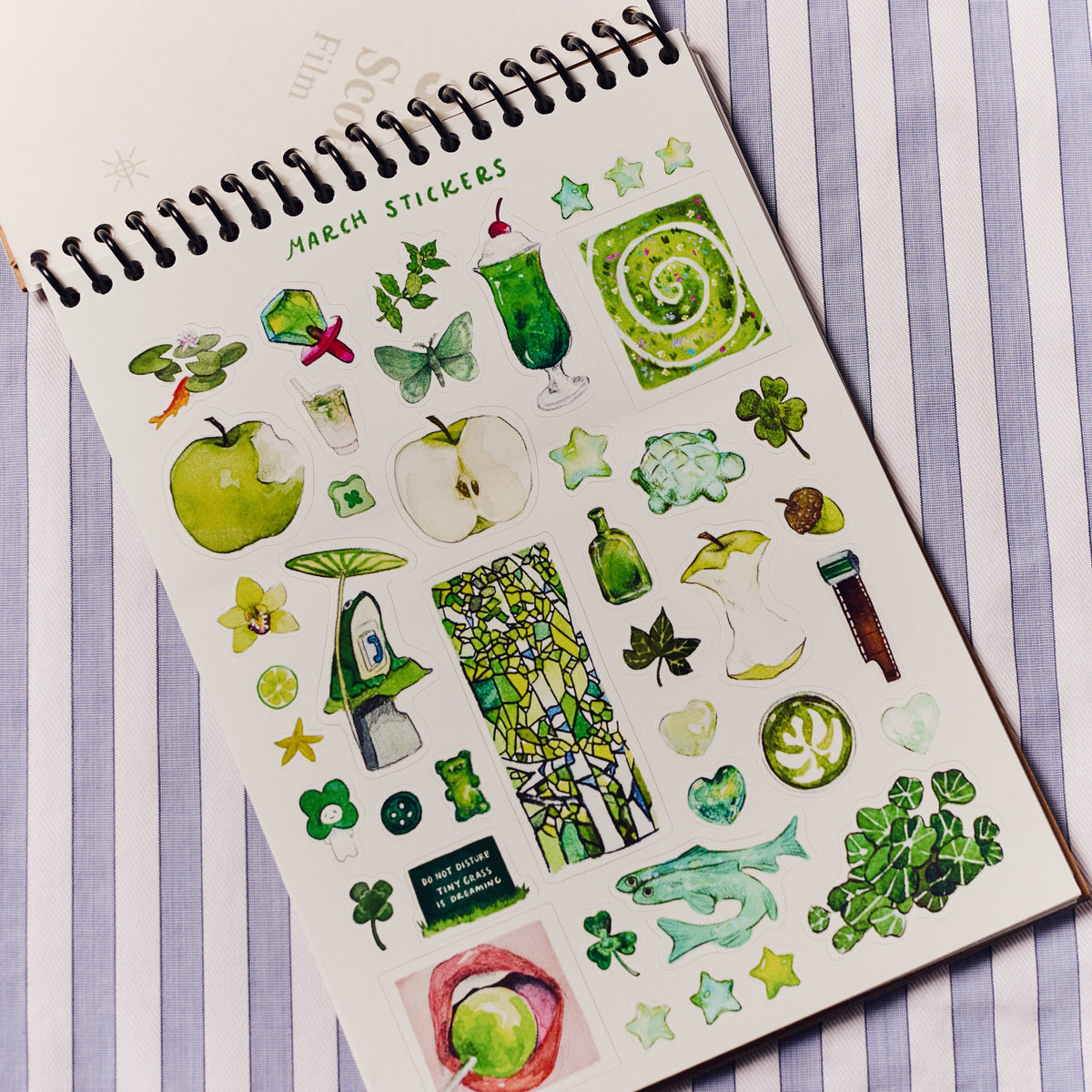 Sheet of March-themed stickers on a notebook with a striped background