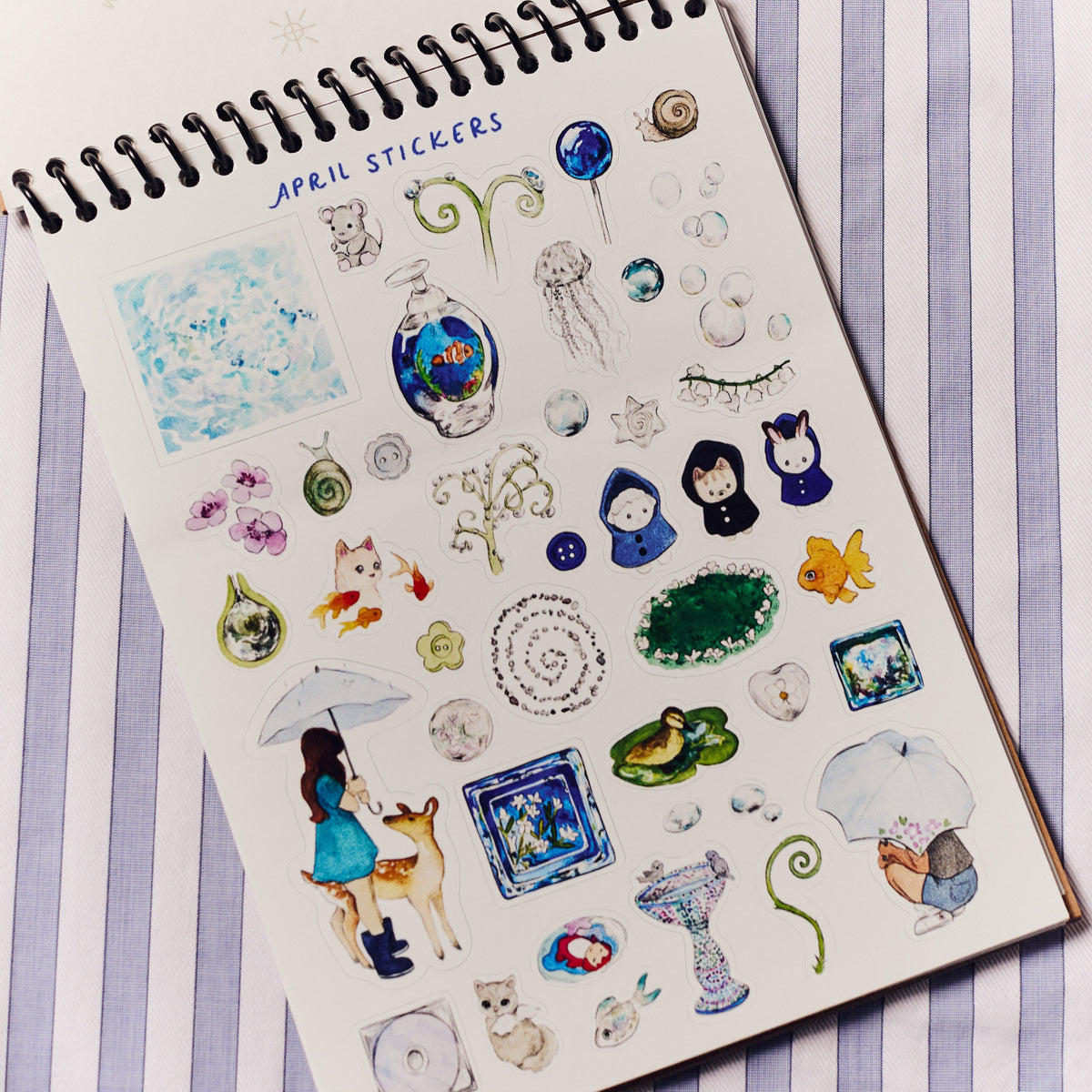 Sheet of decorative stickers on a notebook with 'April Stickers' text, on a striped background.