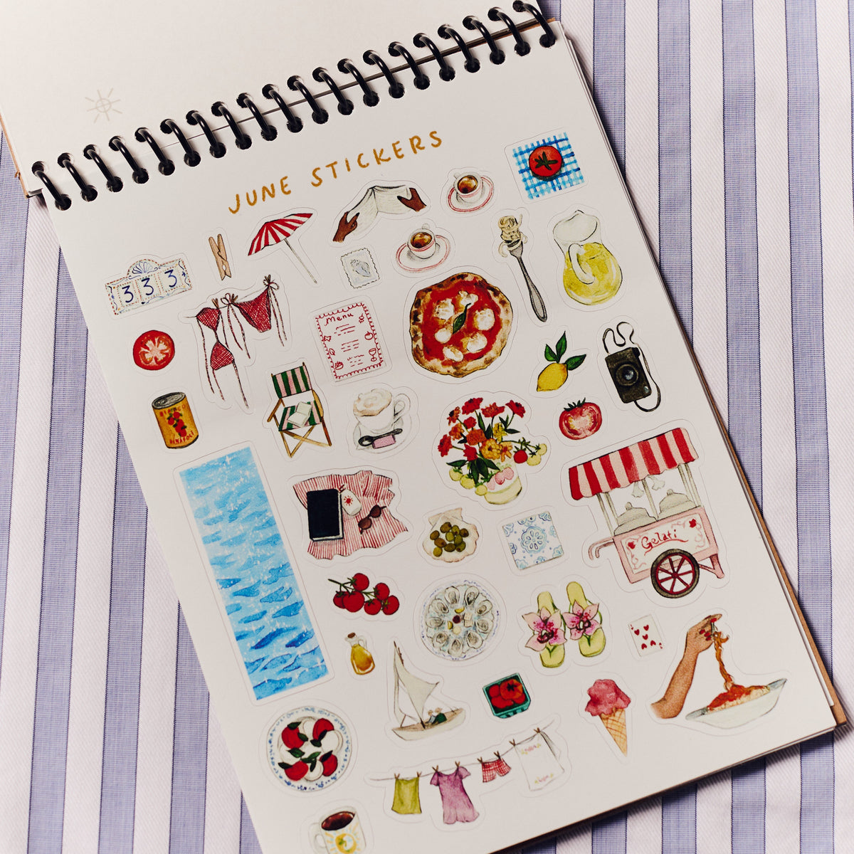 Sheet of June-themed stickers on a notebook with a striped background