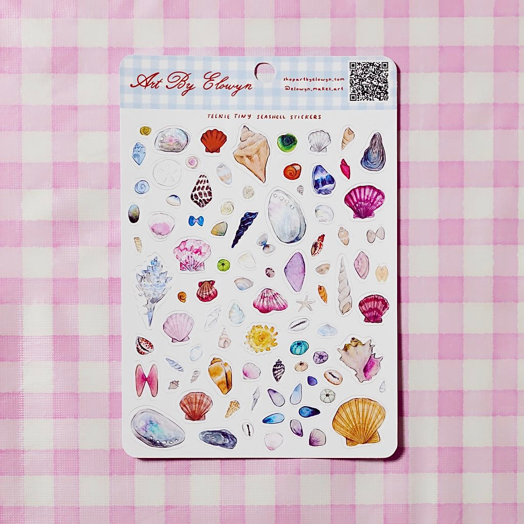 Sheet of decorative stickers with various designs on a pink and white checkered background.